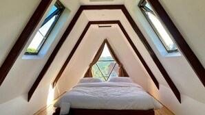 Ein Schlafzimmer mit schrägem Dach und Dachfenstern sowie einem Bett.