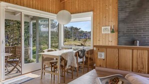 Un intérieur en bois comprenant un coin repas, une cheminée et une vue sur l’extérieur.