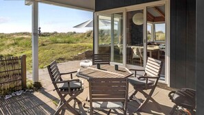 Une terrasse extérieure avec une table et des chaises, un espace salon abrité et une vue sur le paysage environnant.