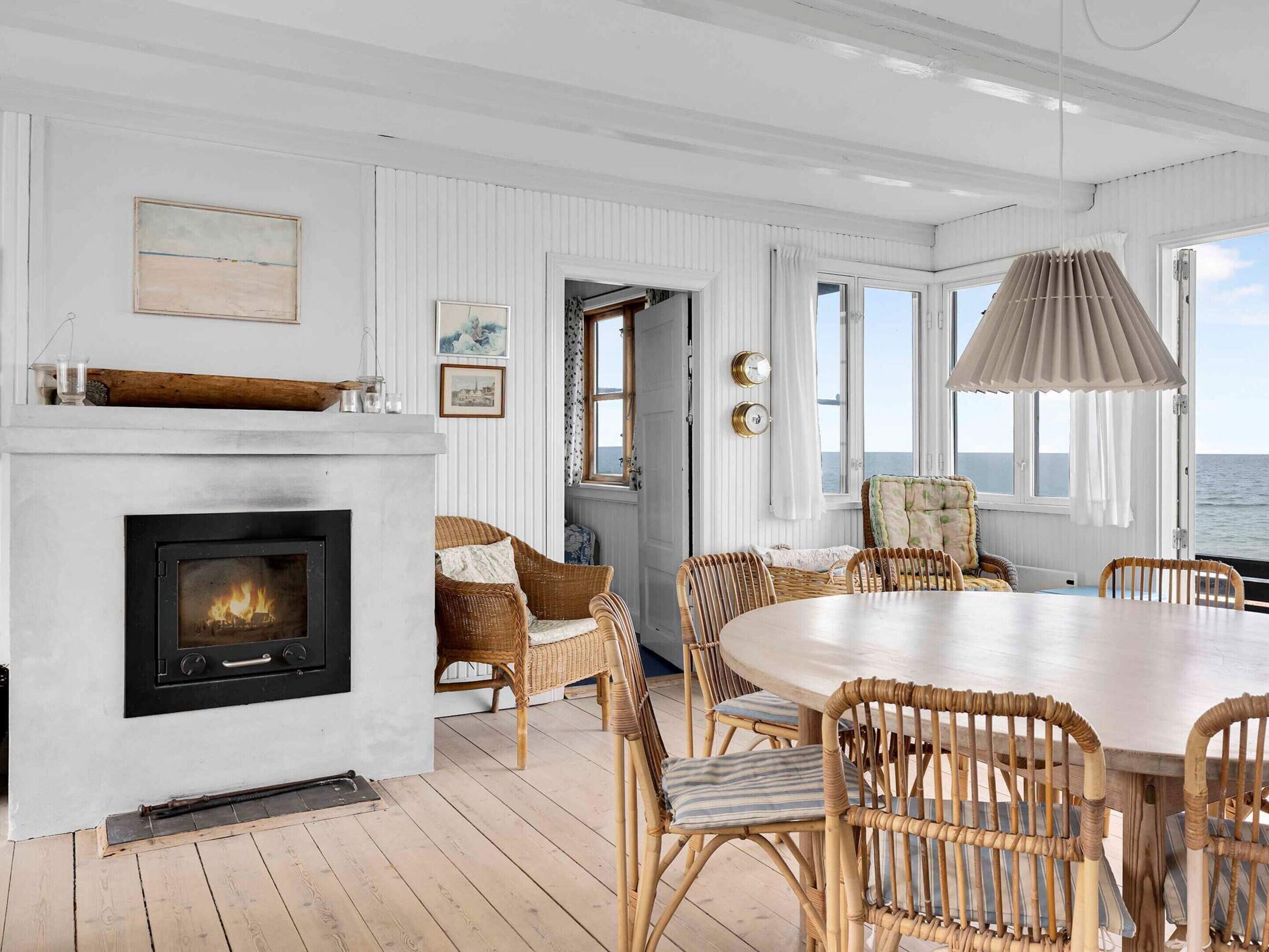Habitación costera con chimenea, muebles de mimbre y vistas al mar.