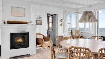 Habitación costera con chimenea, muebles de mimbre y vistas al mar.