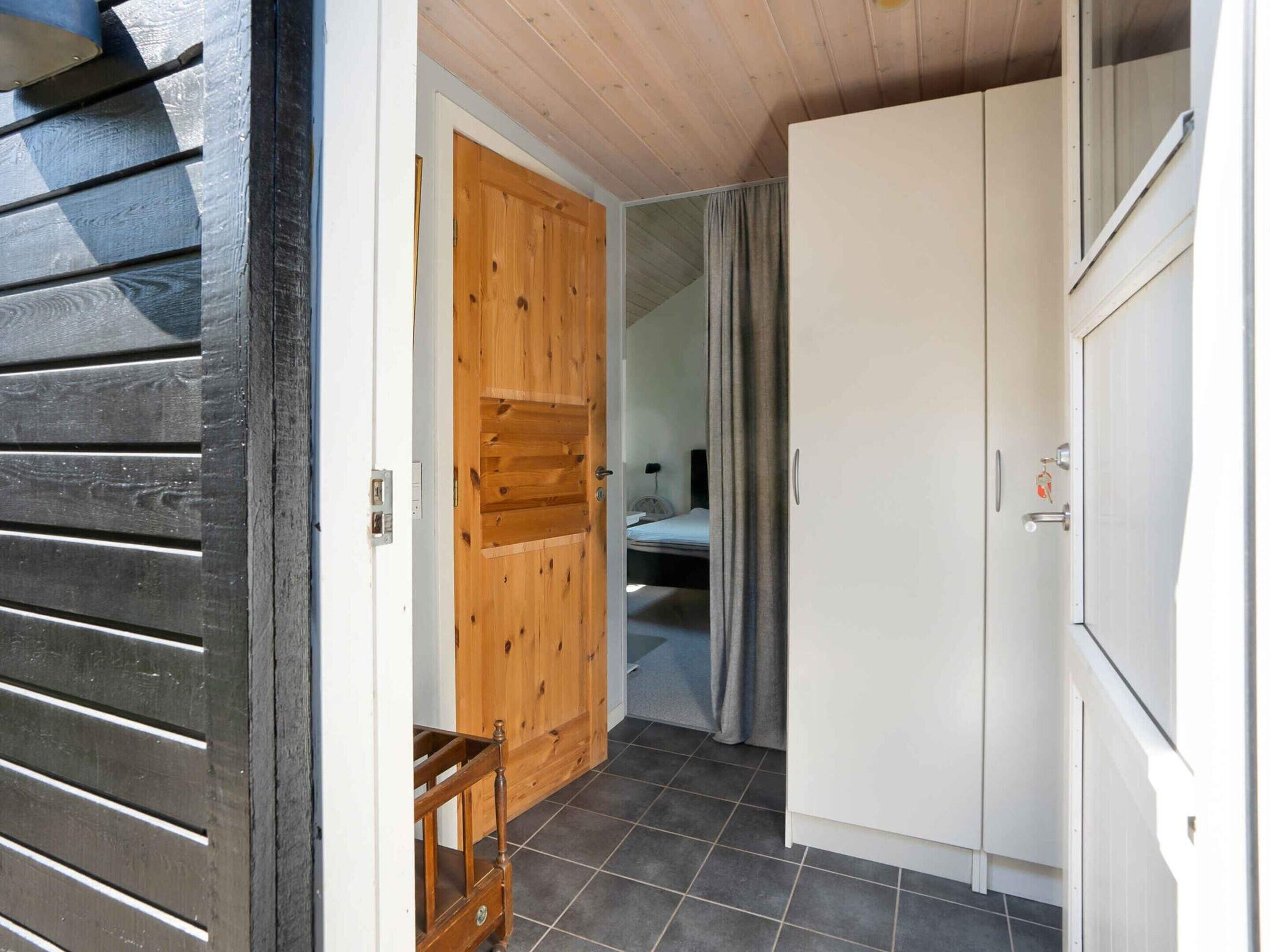 A room with a wooden door, a bed, a wardrobe, and a small table.
