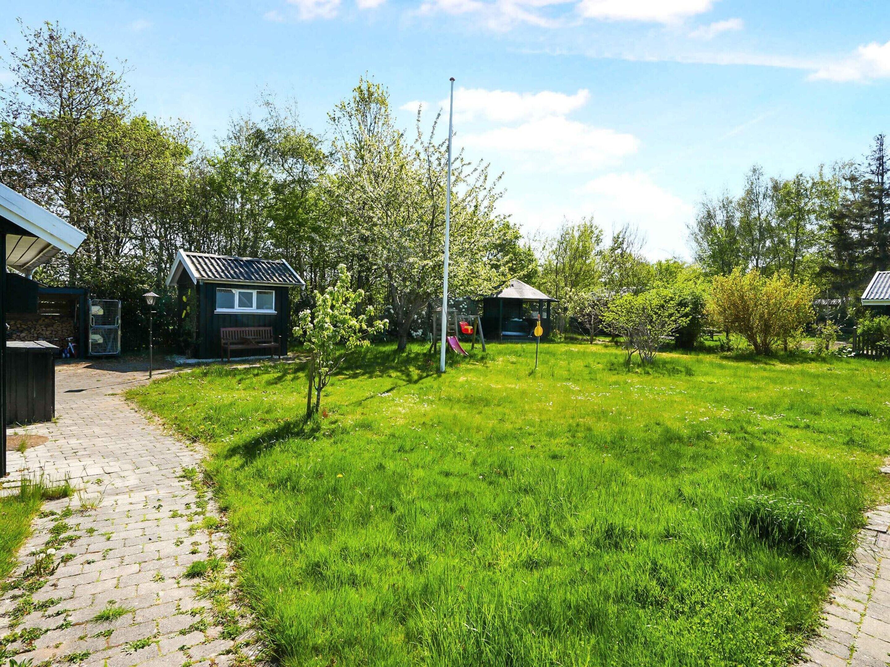 A residential area with a paved walkway, a grassy yard, and two small houses with solar panels.