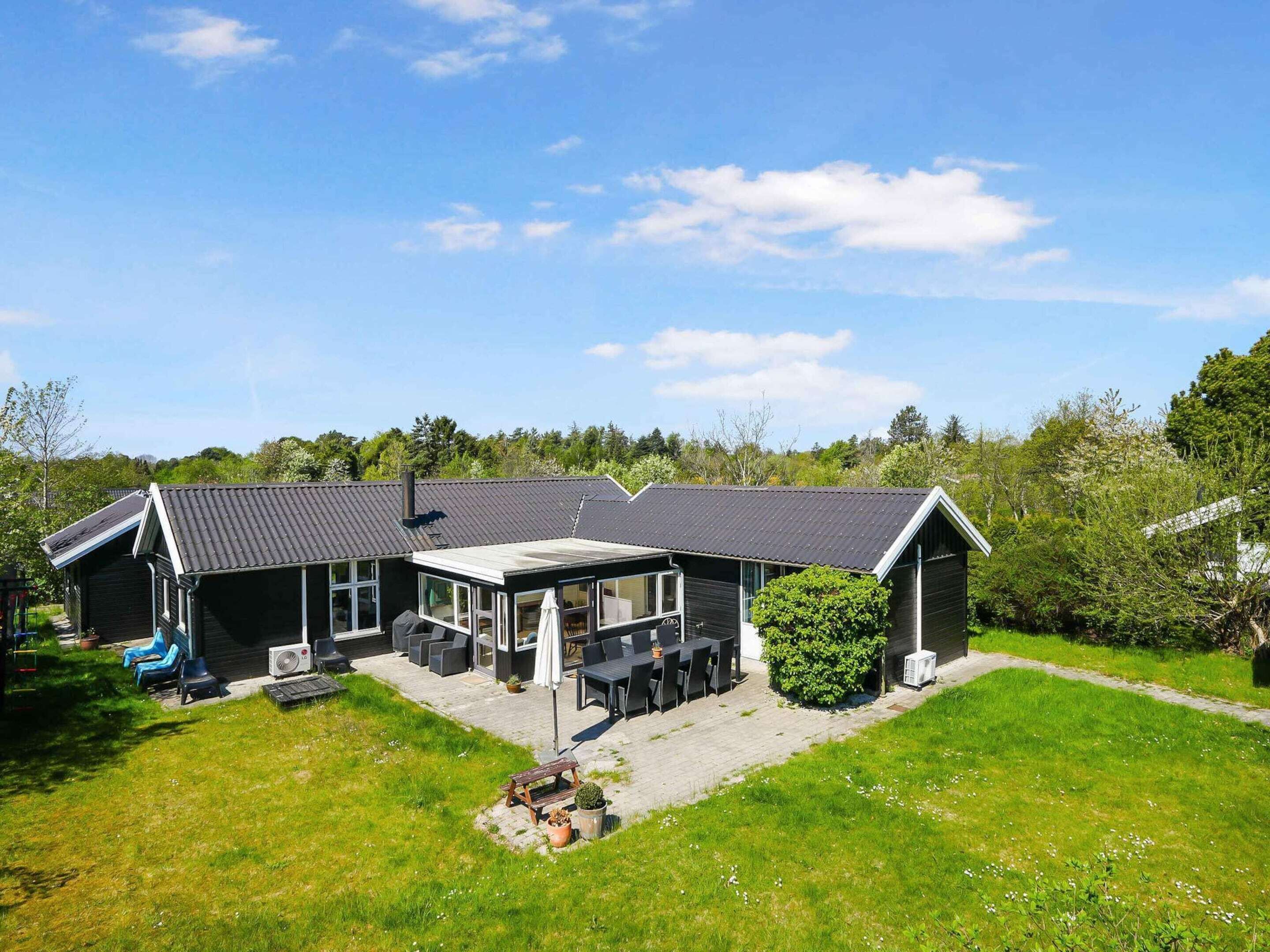 A two-story house with a covered patio, outdoor seating, and a lawn.