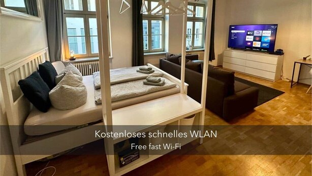 Et moderne hotelværelse med seng, sofa, fjernsyn og udsigt over byen.