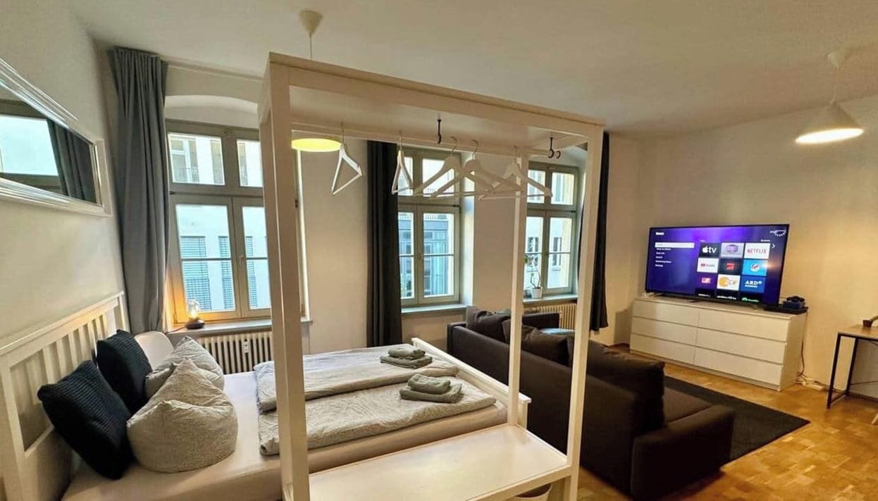 Una habitación de hotel moderna con una cama, un sofá, un televisor y vistas a la ciudad.