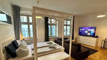 Una habitación de hotel moderna con una cama, un sofá, un televisor y vistas a la ciudad.