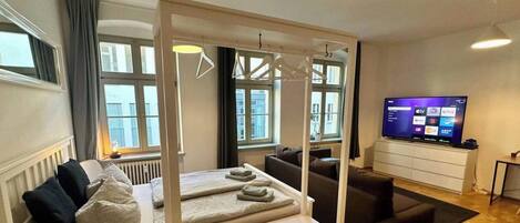 Una habitación de hotel moderna con una cama, un sofá, un televisor y vistas a la ciudad.