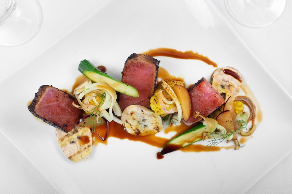 Un piatto bianco rettangolare con un'insalata di carne, verdure e salsa.