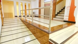A hotel lobby with a tiled floor, a metal railing, and a staircase. - Tickle Hotel (Gondokusuman)