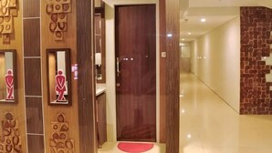 A hallway with a wooden door, a mirror, and a red mat on the floor. - Tickle Hotel (Gondokusuman)