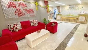 A reception area with a red sofa, a white coffee table, and a reception desk. - Tickle Hotel (Gondokusuman)