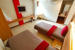 A hotel room with two beds, a TV, a desk, and a mirror. - Tickle Hotel (Gondokusuman)