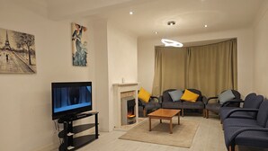 Una sala de estar con una televisión de pantalla plana, una chimenea, dos sofás y una mesa de centro.
