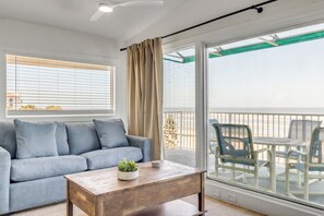 A balcony with a view, a sofa, a coffee table, and a dining set.