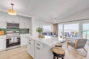 A modern kitchen with white cabinetry, a stainless steel oven, and a large island with stools.