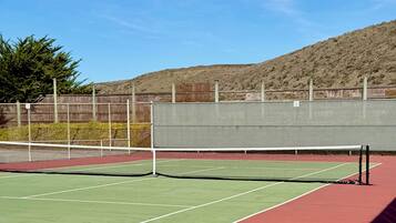 A tennis court with a net, green and red playing areas, and a fence with numbers 7 and 8.