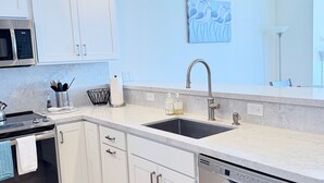 Una cocina moderna con gabinetes blancos, electrodomésticos de acero inoxidable, un lavamanos doble y un lavavajillas.