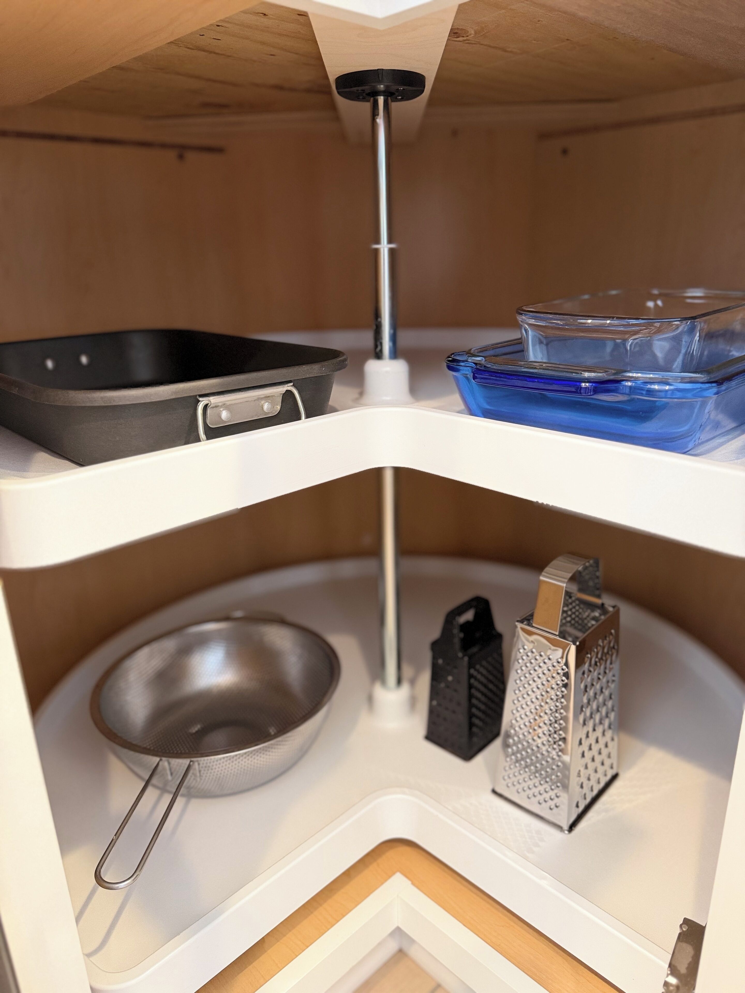 Een keuken met een zwarte koekenpan, een blauwe glazen container, een metalen zeef en een rasp.