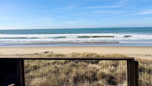 Vista de una playa con orilla arenosa y una zona cubierta de hierba en primer plano.