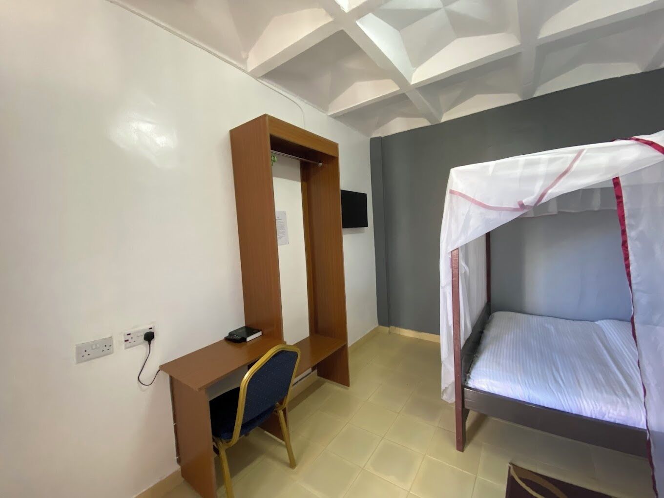Una camera da letto con un letto a castello, una scrivania con una sedia e un televisore montato a parete.