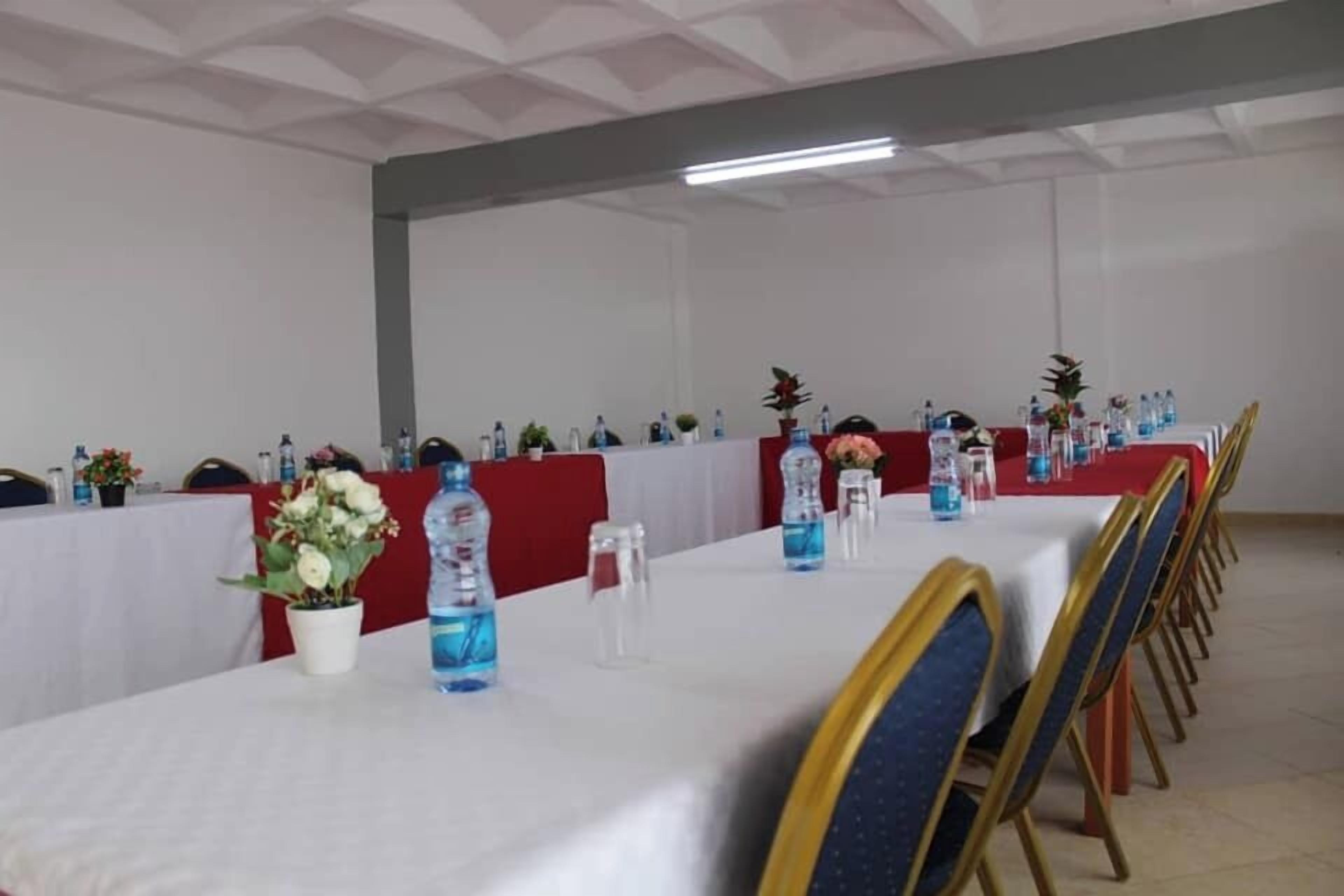 A conference room with tables set up for a meeting, equipped with water bottles, floral centerpieces, and chairs.