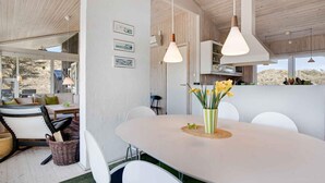 A modern dining area with a large oval table, white chairs, and hanging pendant lights. - 5 Star Holiday Home in Pandrup (Pandrup)