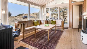 A modern interior with a wooden ceiling, large windows, a sofa, a coffee table, and a TV. - 5 Star Holiday Home in Pandrup (Pandrup)
