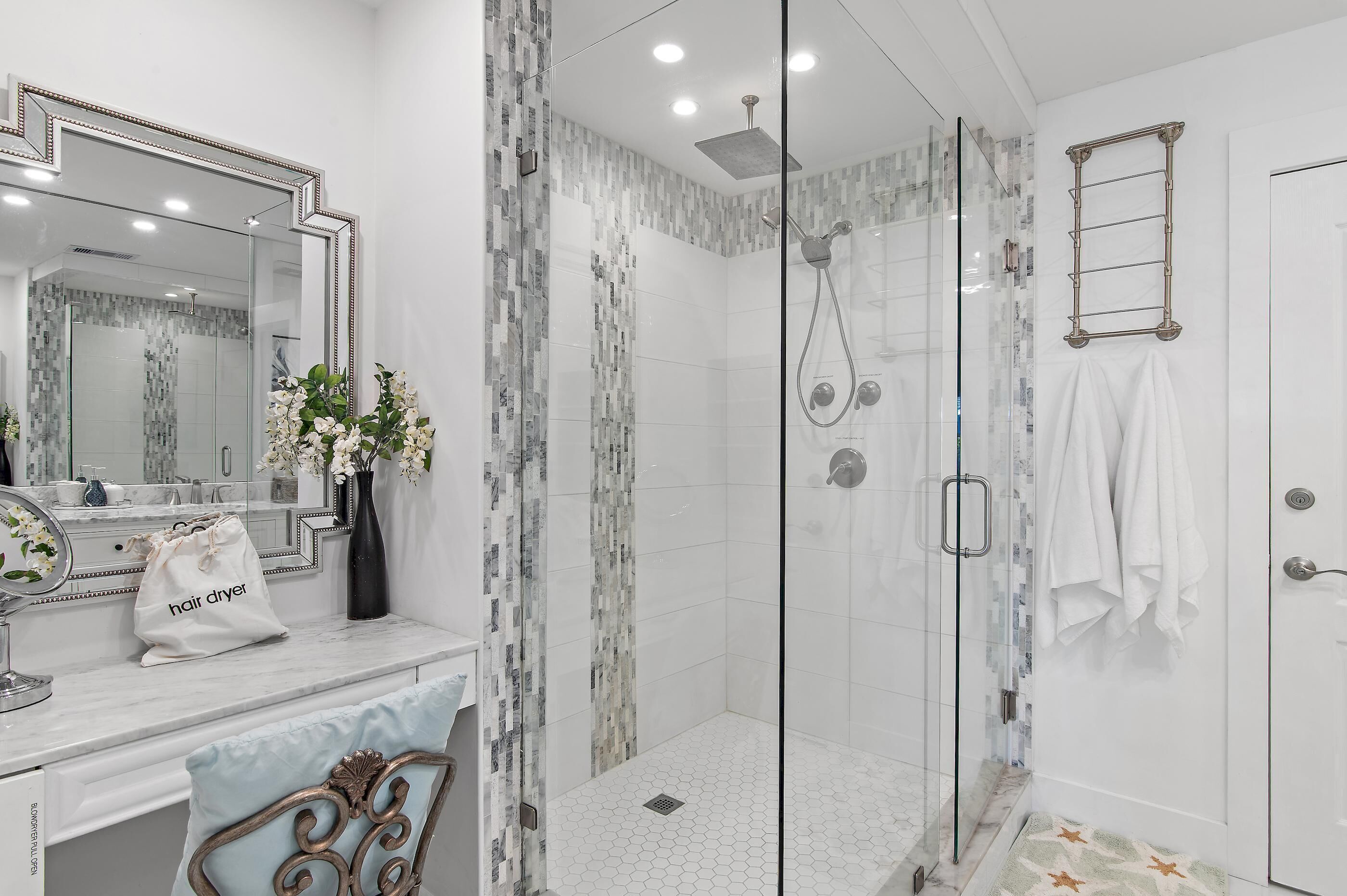 Une salle de bain moderne avec une douche à parois de verre, un meuble-lavabo avec un miroir et un porte-serviettes.