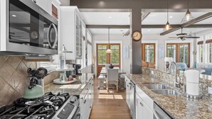 A modern kitchen with granite countertops, stainless steel appliances, and a dining area with natural light.
