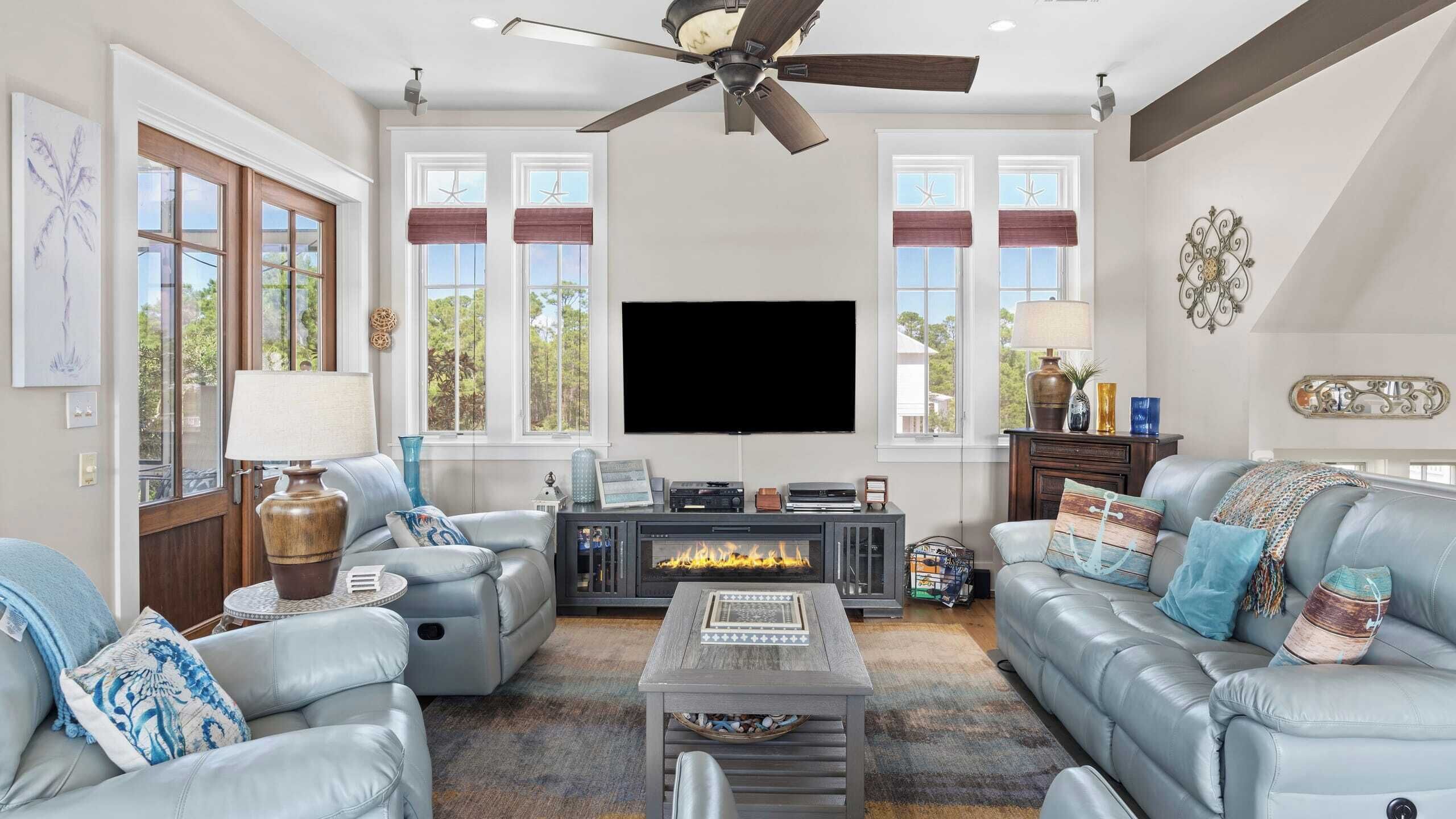 A living room with a fireplace, leather sofas, a coffee table, and a flat-screen TV.