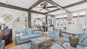 A spacious living room with a high ceiling, a dining area, and a kitchen.