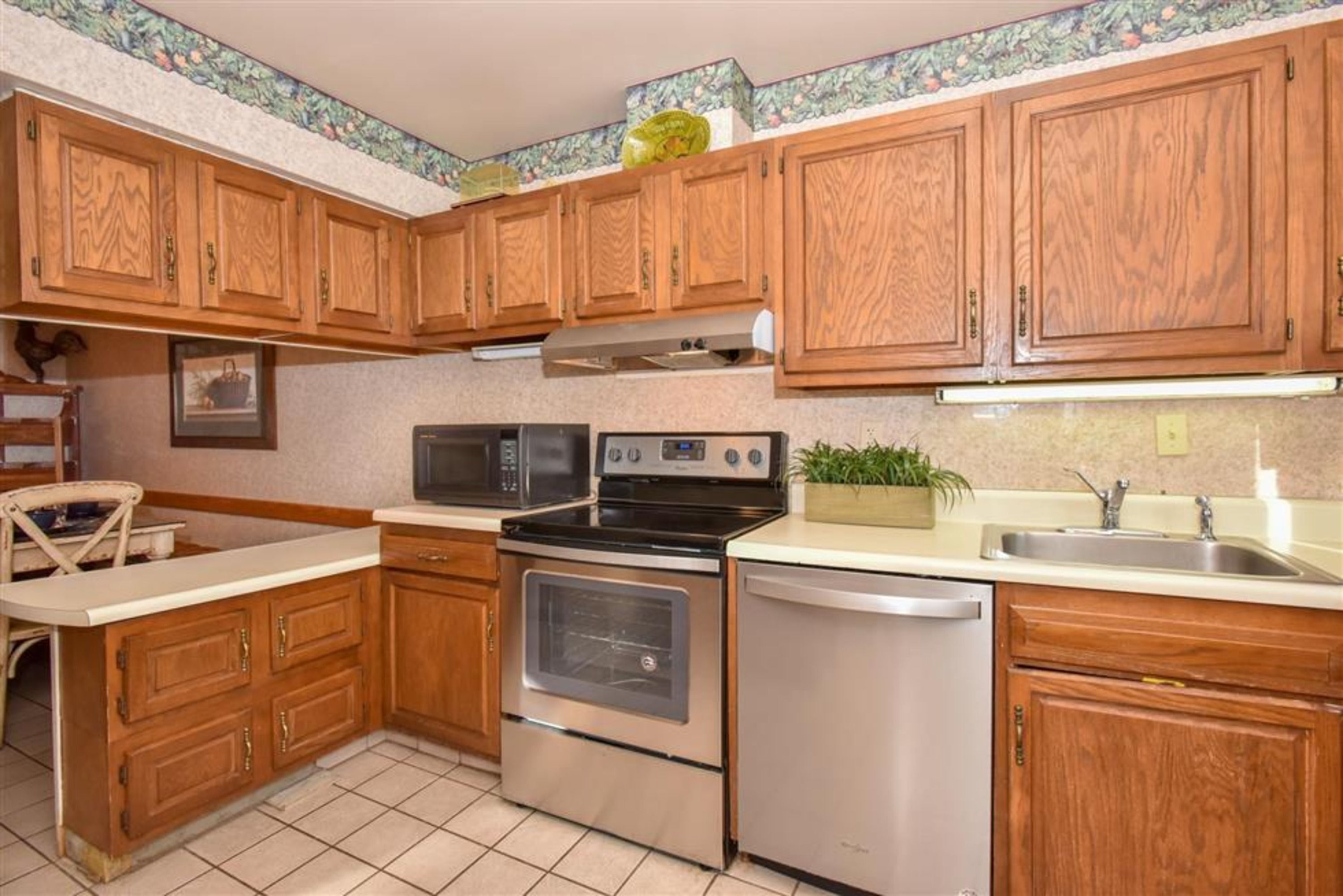 A kitchen with wooden cabinets, a microwave, an oven, and a dishwasher.