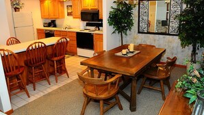 A kitchen with wooden cabinets, a dining table with chairs, and a large mirror. - Charming 2BR Villa | Cozy Stay w/ Pools + Shuttle (Champion)
