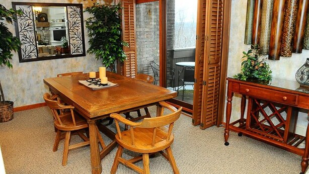 A dining area with a wooden table and chairs, a chandelier, and a view through a glass door to an outdoor patio. - Charming 2BR Villa | Cozy Stay w/ Pools + Shuttle (Champion)