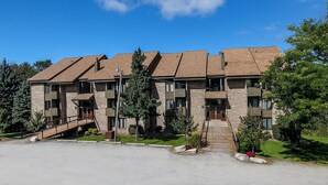 A multi-story building with a brick facade, multiple balconies, and a central entrance with a staircase. - Charming 2BR Villa | Cozy Stay w/ Pools + Shuttle (Champion)