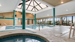 An indoor swimming pool with clear water, a skylight, and a view of the outdoors. - Romar Place 705 (Orange Beach)