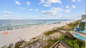 A beach resort with a swimming pool, beach umbrellas, and a view of the ocean. - Romar Place 705 (Orange Beach)