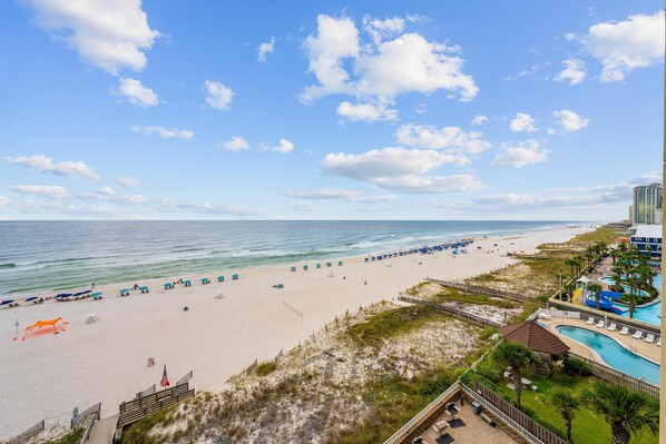 A beach resort with a swimming pool, beach umbrellas, and a view of the ocean. - Romar Place 705 (Orange Beach)