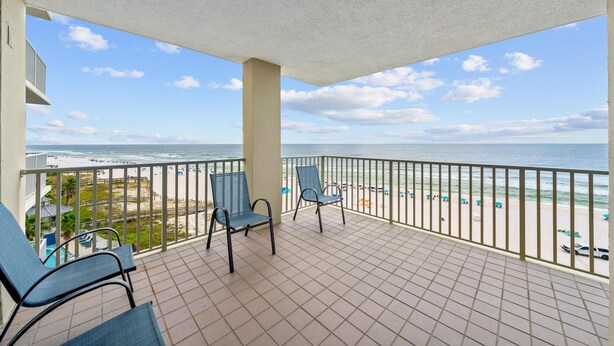 A balcony with two chairs, a view of the beach, and a clear sky. - Romar Place 705 (Orange Beach)