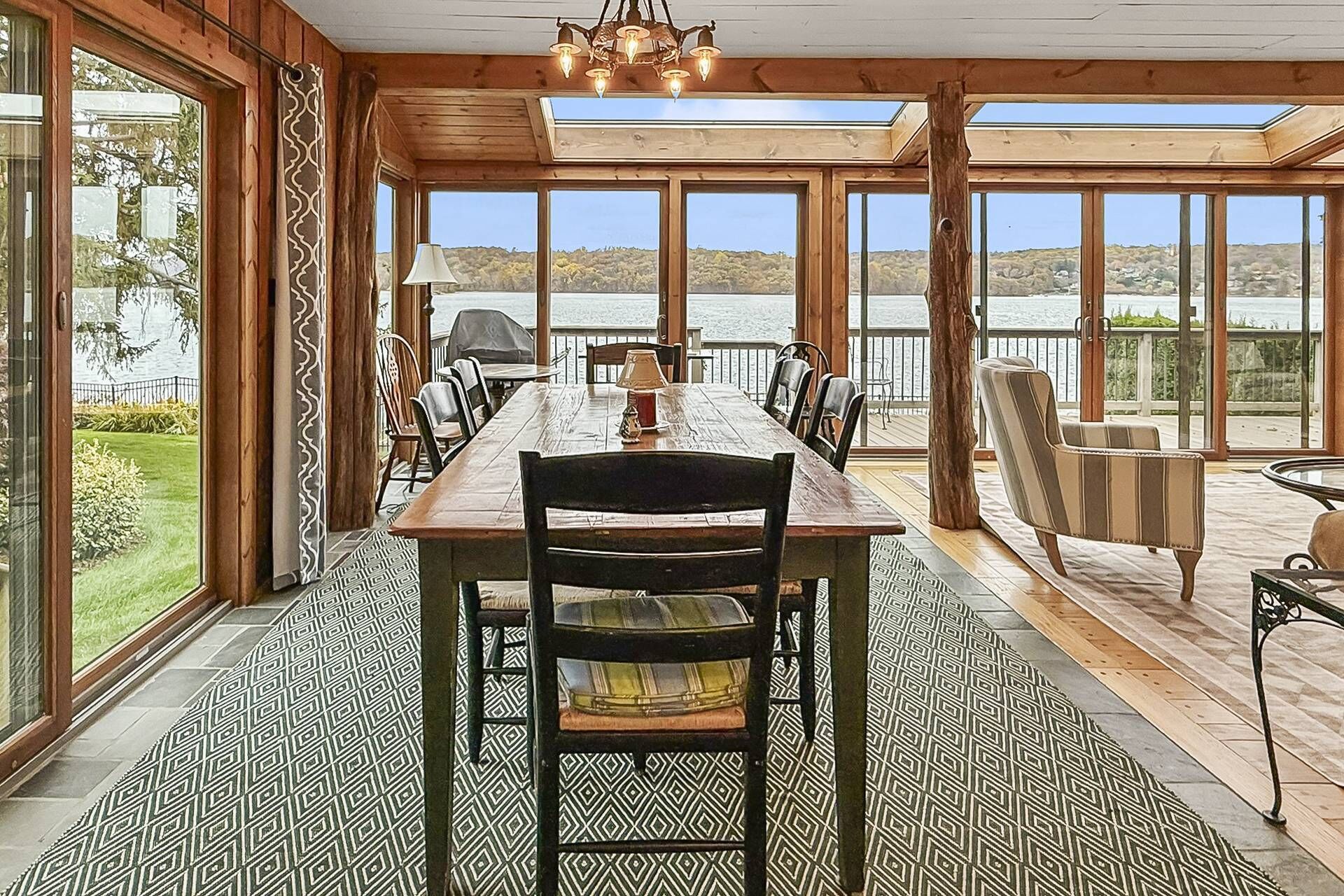 Un espace repas avec une longue table en bois, des chaises et une vue sur un lac.