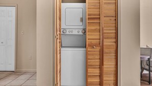 A laundry room with a washing machine and dryer, wooden closet doors, and a tiled floor. - 2-Story Townhouse in the Heart of Downtown (Cleveland)