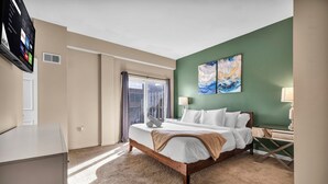 A hotel room with a bed, a desk, a TV, and artwork on the wall. - 2-Story Townhouse in the Heart of Downtown (Cleveland)
