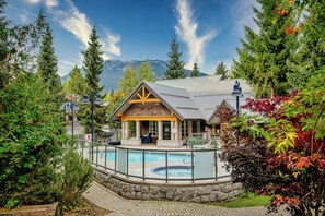 A lodge with a pool, surrounded by trees and mountains.
