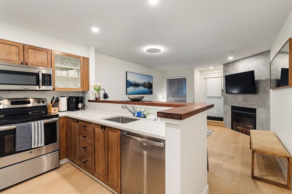 A modern kitchen with stainless steel appliances, wooden cabinets, and a built-in dishwasher.