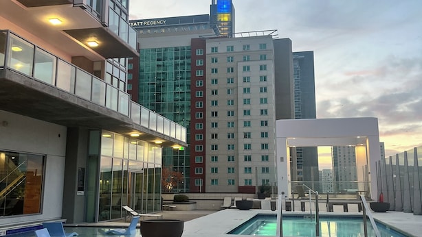 Un hôtel doté d’une piscine sur le toit, d’une architecture moderne et offrant une vue sur les autres bâtiments.