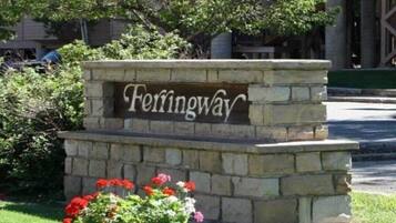 A stone sign with the name 'Ferringway' surrounded by a small garden with red flowers.