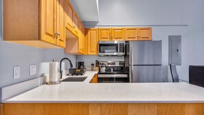 A kitchen with wooden cabinets, stainless steel appliances, and a white countertop. - Cozy studio in delightful Cleveland with gym, parking and AC (Cleveland)