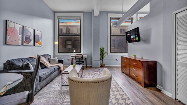 A modern living room with a sofa, coffee table, and a TV mounted on the wall. - Cozy studio in delightful Cleveland with gym, parking and AC (Cleveland)