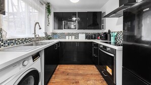 A compact kitchen with a washing machine, a refrigerator, and a microwave.